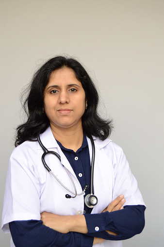 Vertical photo of one confident woman nurse or doctor or health care worker,  physician over gray background with copy space for text.