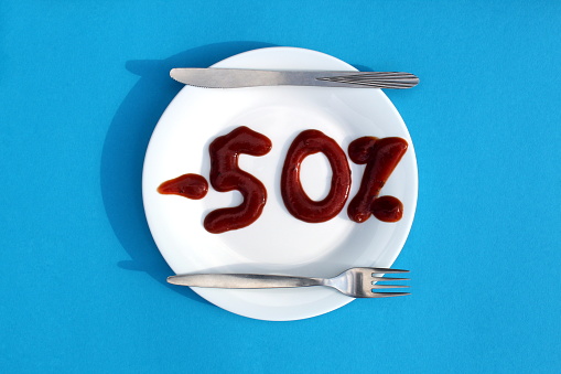 On a white plate discount minus 50 percent with ketchup.