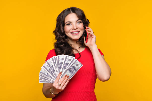 woman holds fan dollars and cell stock photo