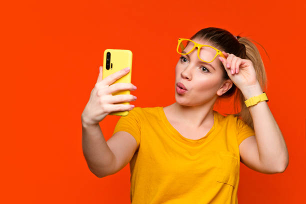 Girl in glasses with a mobile phone in a photo studio stock photo