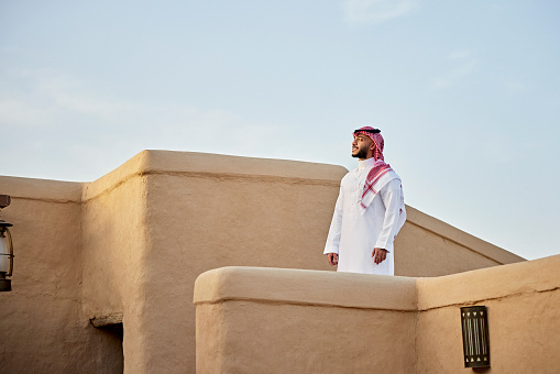 Hombre saudí adulto medio de pie al aire libre en medio de las ruinas de At-Turaif photo