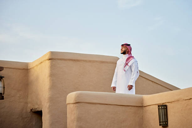 Mid adult Saudi man standing outdoors amidst At-Turaif ruins stock photo