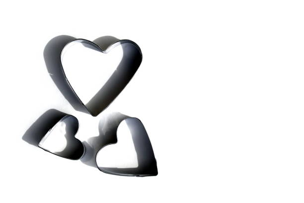 Three hearts of different sizes for cutting cookie dough on a white background.