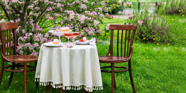 istock Festive spring romantic table setting with dessert in blossom garden. Banner 1391752230