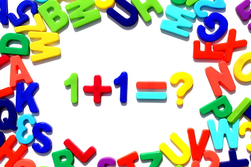 Bright multi-colored English alphabet lies on a white background in the form of a circle. In the middle is a math example.