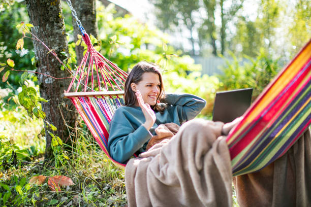 istock Young woman working with laptop from backyard in hammock 1391754531