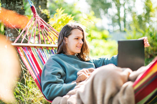 istock Young woman working with laptop from backyard in hammock 1391755205