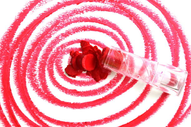 Broken red lipstick lies on a white background.