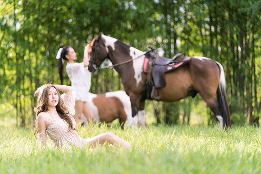 Beautiful woman and horse in the field at spring. Happy woman in white dress with horse in summer field forest.