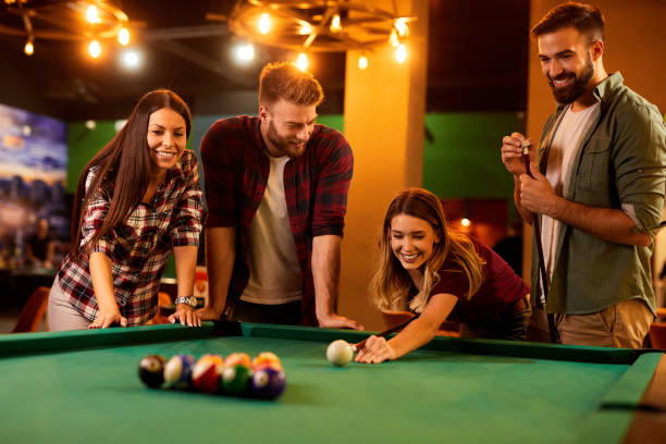 istock Group of friends having fun while playing pool in a local pool hall 1391759185
