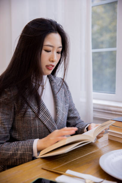 istock Young asian women reading a book at restaurant 1391760334