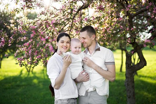 Portrait of a young family with a child. Happy young family spending time outdoor on a summer day. Happiness and harmony in family life. Happy family concept.