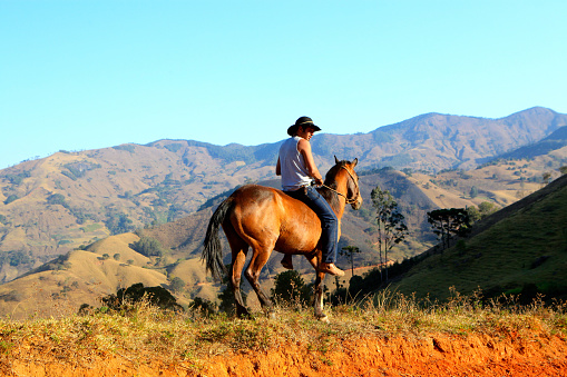 Member of the Asurini Indigenous Tribe of Baixo Amazonas, Rio Xingu, Brazil, riding  a horse with views to the mountains around the protected reserve,