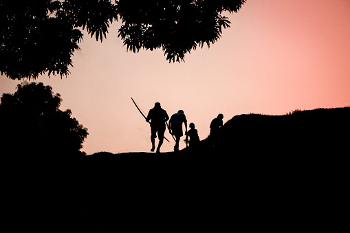 Silhouette of the indigenous men of the Asurini tribe of the Xingu River, Baixo Amazonas, Brazil, going hunting during sunset.
