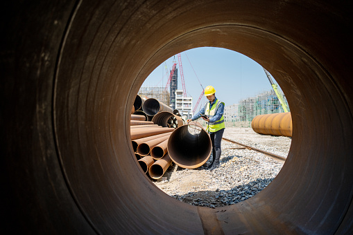 A female engineer used a measuring instrument to measure the quality of steel pipe