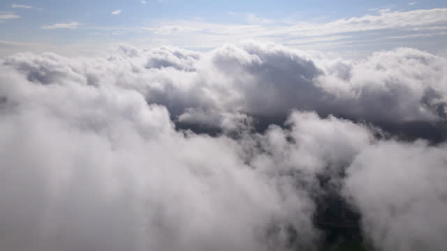 Flying through the amazingly beautiful cloudscape. Picturesque timelapse of white fluffy clouds moving softly on the clear blue sky. Direct view from the cockpit