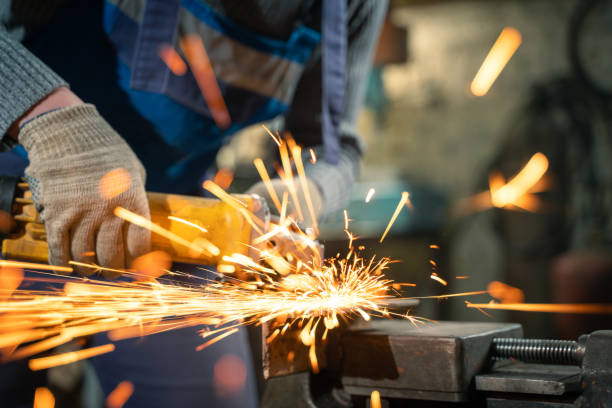 istock Locksmith in special clothes and goggles works in production. Metal processing with angle grinder. Sparks in metalworking 1391769929