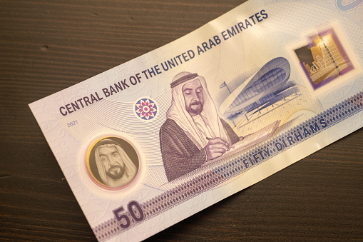 Currency of the United Arab Emirates (UAE) - New 2021 Fifty Dirham notes spread out on a black background. Money exchange.