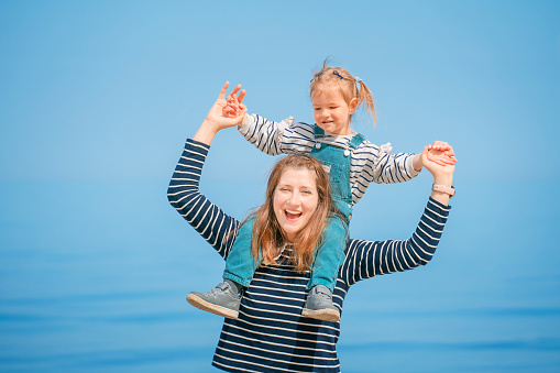 Smiling mother and daughter playing on the beach