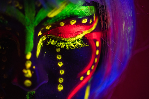 Portrait of a beautiful young woman wearing fluorescent makeup. Close-up.
