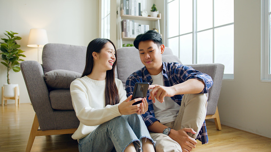 Asian couple man and woman using mobile phone, spend time together at home, Asian couple family lifestyle concept