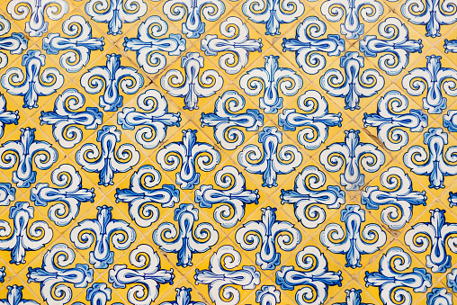 Wall of patterned tiles in vibrant yellow and blue colors on the facade of the Central Market Valencia, Spain.