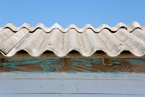 Old aged dangerous roof made of corrugated asbestos panels - one of the most dangerous materials in buildings and construction industry so-called hidden killer.