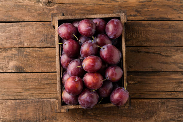 istock Juicy plums in box on rustic wooden table. Top view 1391777247