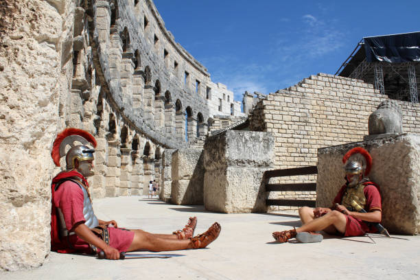 Inside a Roman Colloseum, in Pula, Croatia Two Roman Centurions sitting on floor inside Roman Colloseum, Pula, Croatia gladiator shoe stock pictures, royalty-free photos & images