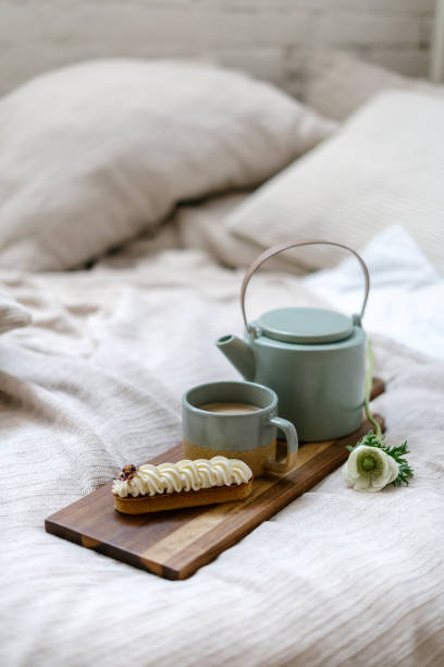 istock Coffee in cup, beverage in teapot and eclair on cutting board 1391781040