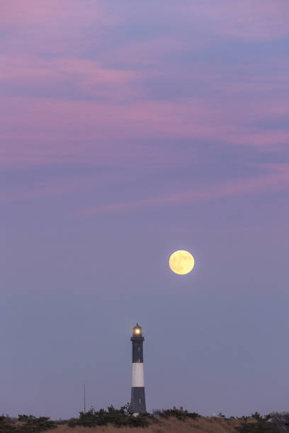 istock Full moon rising behind a tall stone lighthouse just after sunset. Fire Island 1391782403