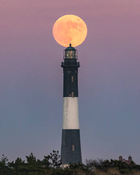 istock Full moon rising behind a tall stone lighthouse just after sunset. Fire Island 1391782419