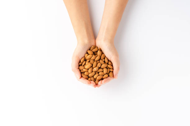 Overhead shot of woman’s hands holding almonds isolated on white background stock photo