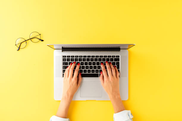 istock Modern office desktop with female hands working on laptop. Workspace with eyeglasses 1391783809