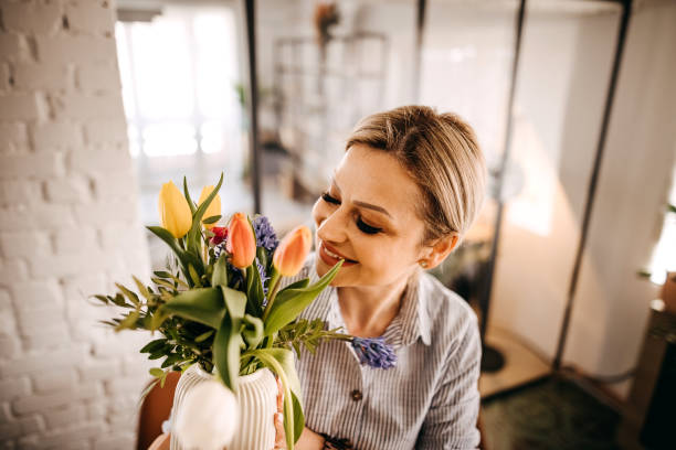 istock Young woman arranging tulips at home 1391784071