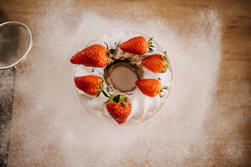 Cake decorated with strawberries and sprinkled with powdered sugar