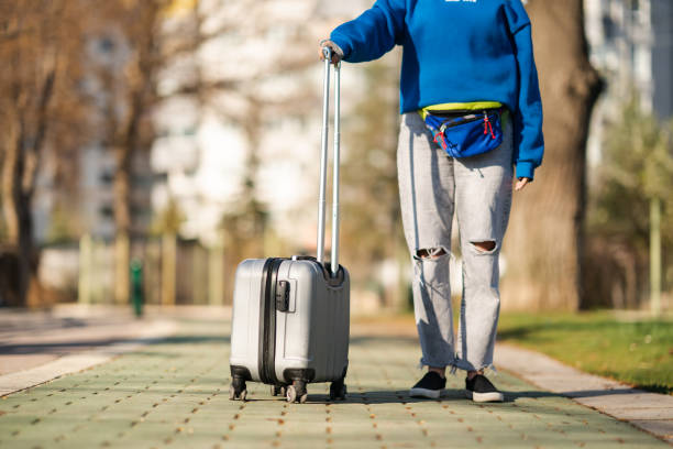 istock Woman pulling a suitcase in the park on a sunny day 1391785117