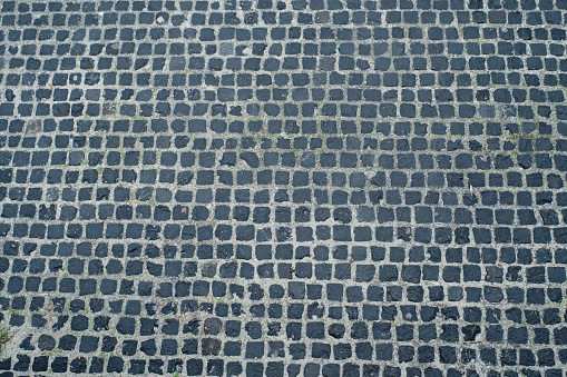 View from above onto stone pavement of urban street. Wet stones after rain