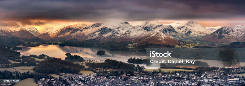 Latrigg Winter Sunrise Overlooking Derwentwater, Lake District, UK. Panoramic view of Derwentwater in the Lake District on a Winter morning with snow on mountains. National Park Stock Photo