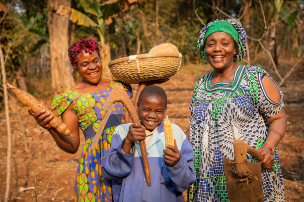 grupo de agricultores africanos se divierten en los campos, tienen azadas en sus manos y están listos para arar el campo, niño con la canasta de cultivos en la cabeza - africa farmer african descent agriculture fotografías e imágenes de stock