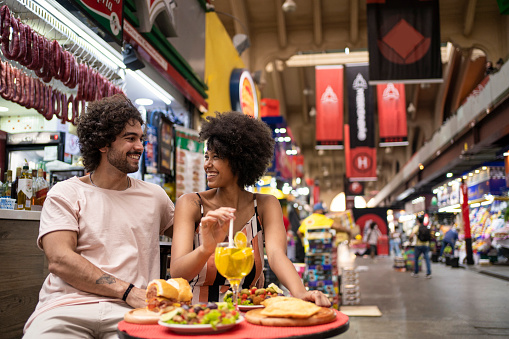 Portrait of beautiful tourists couple eating traditional food in the municipal market of São Paulo