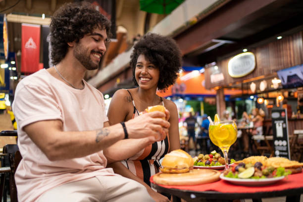 retrato de una hermosa pareja de turistas comiendo comida tradicional en el mercado municipal - love couple city life urban scene fotografías e imágenes de stock