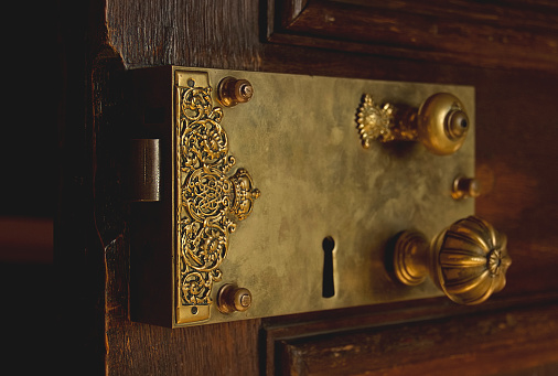 Close up of an open interior door showing an old rim lock. Antique lock details. Mysteries of the royal court concept. Tell a secret.