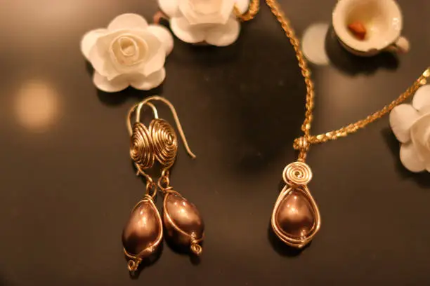 Gold jewellery with brown stones in a black and gold background and white decoration