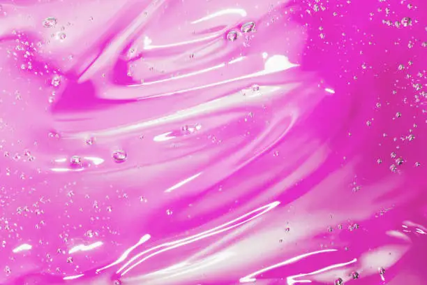Close up macro Aloe vera gel cosmetic texture pink background with bubbles. Lemongrass gel skincare product. antibacterial liquid with aloe vera, moisturizing. Serum texture. Hand sanitizer