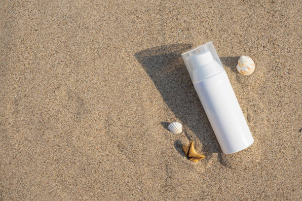 istock Unbranded cosmetic flacon with moisturizing liquid. Summer decorations, seashell and starfish, sand background. Cream or lotion. Mockup style. Beauty concept. Top view 1391800110