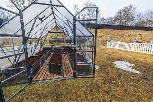 Beautiful view of garden interior with greenhouse prepared for planting vegetables in early spring. Sweden.