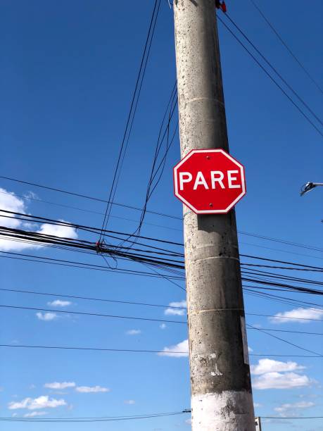 poste de la calle con cableado de energía eléctrica y letrero de tráfico bajo el fondo natural del cielo azul en un día soleado - poste telegráfico fotografías e imágenes de stock