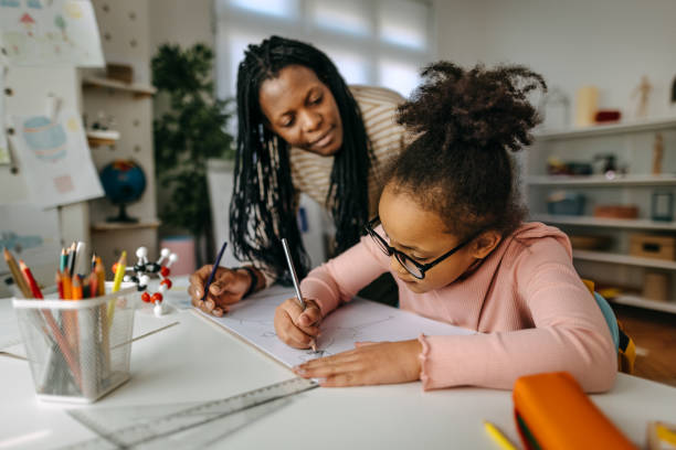 istock Mother assisting daughter in writing homework at home 1391805963