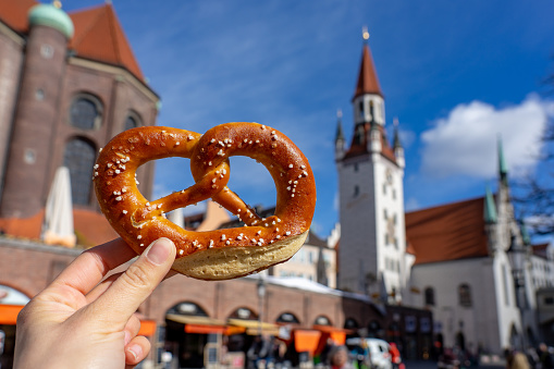holding bayern style pretzel on the victuals market with altes rathaus background in munich .